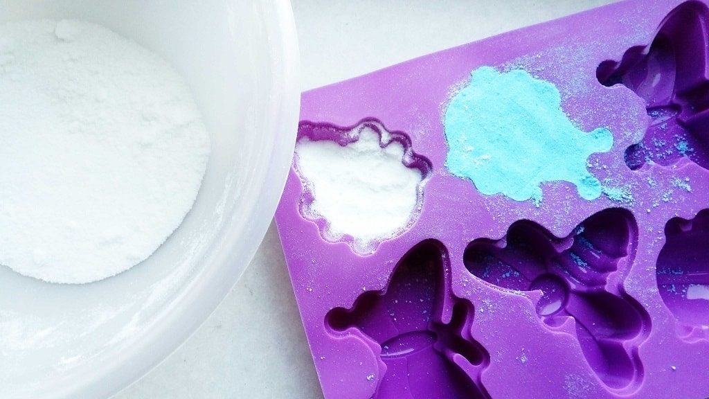 Placing bath bomb mixture into molds for kids bath bombs Placing bath bomb mixture into molds for kids bath bombs