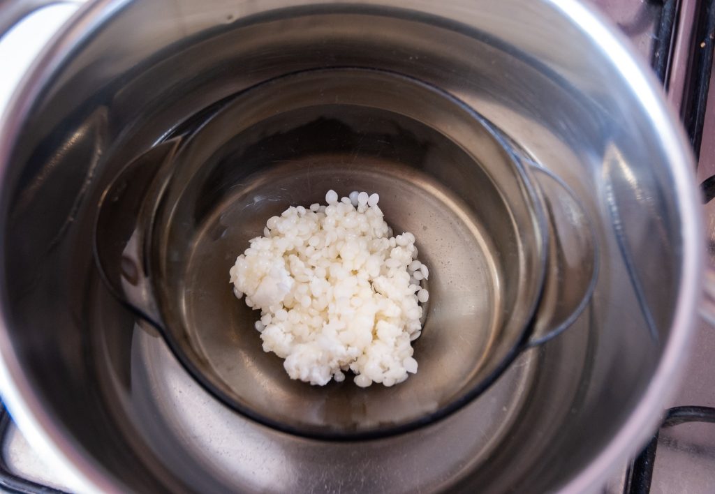 melting ingredients for lip balm melting shea butter, argan oil and beeswax in a pot-min