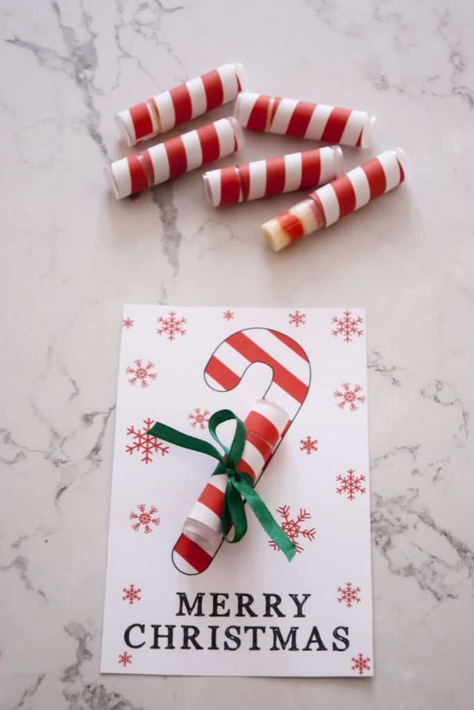 DIY candy cane lip balms with red white labels next to diy lip balm Christmas card