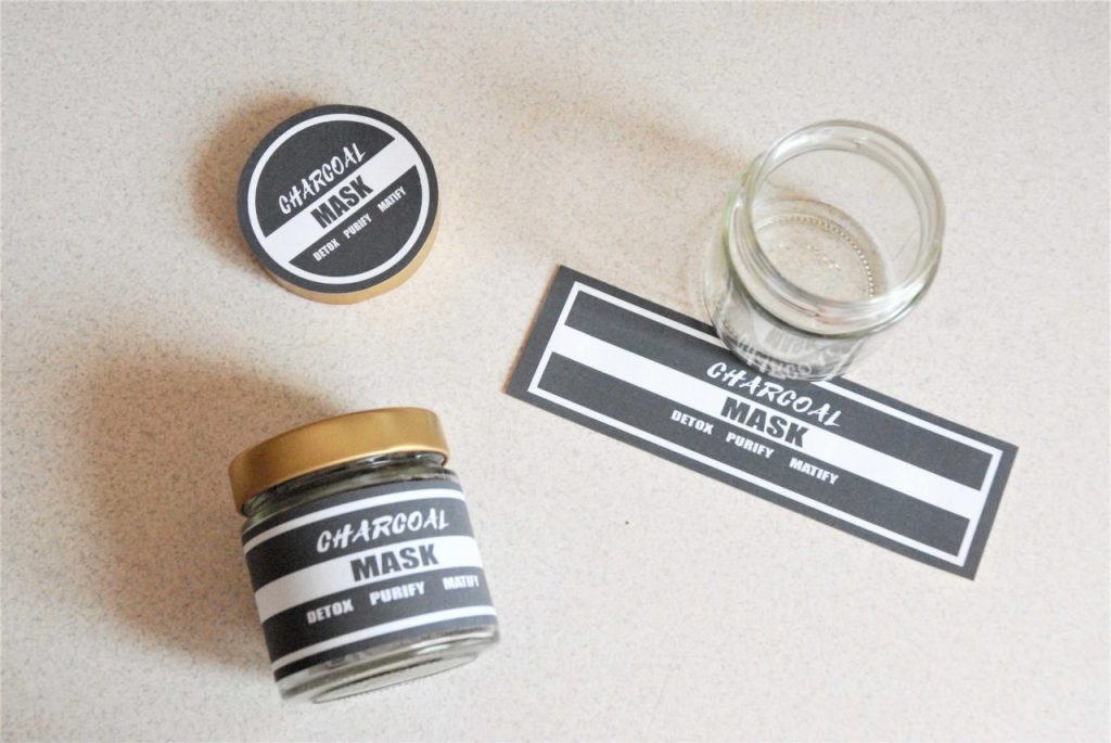 charcoal mask labels displayed on the jar with diy charcoal and clay mask. next to it empty jars and printed mask labels