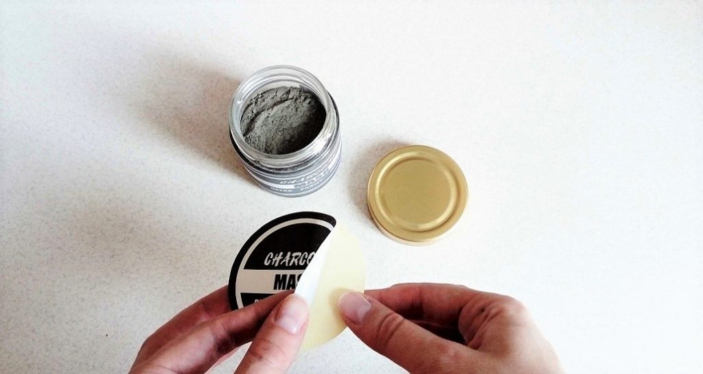 sticking printed charcoal mask label on the jar