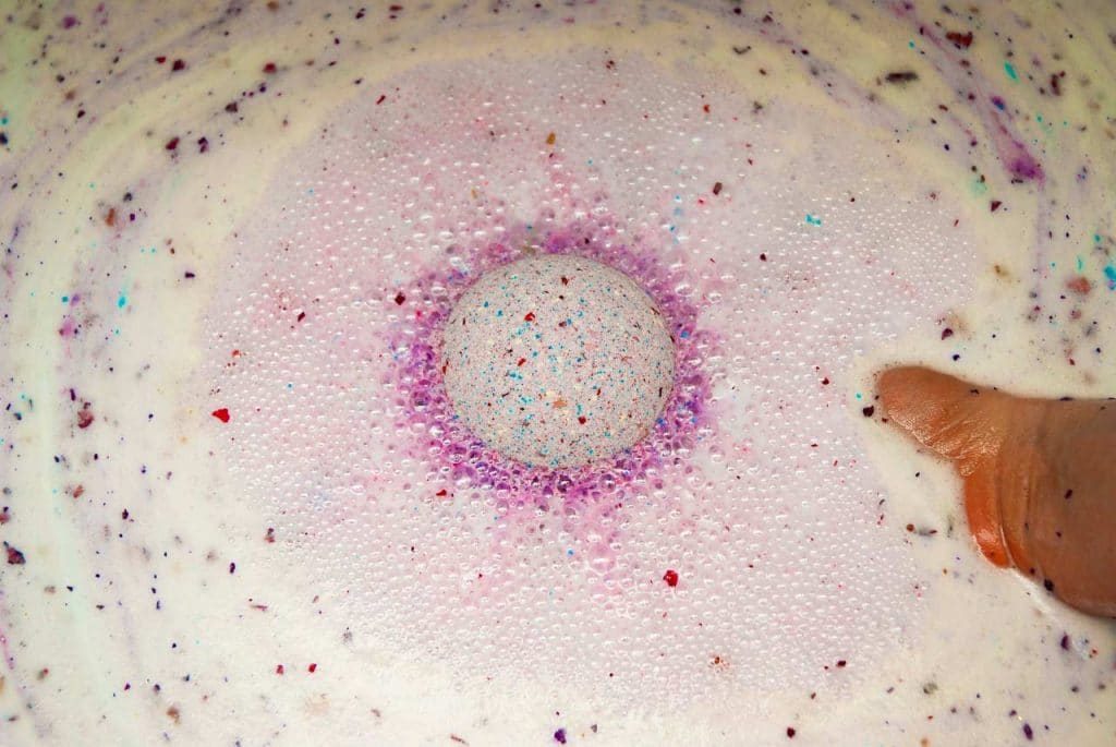 purple diy foaming bath bomb with rose petals in water
