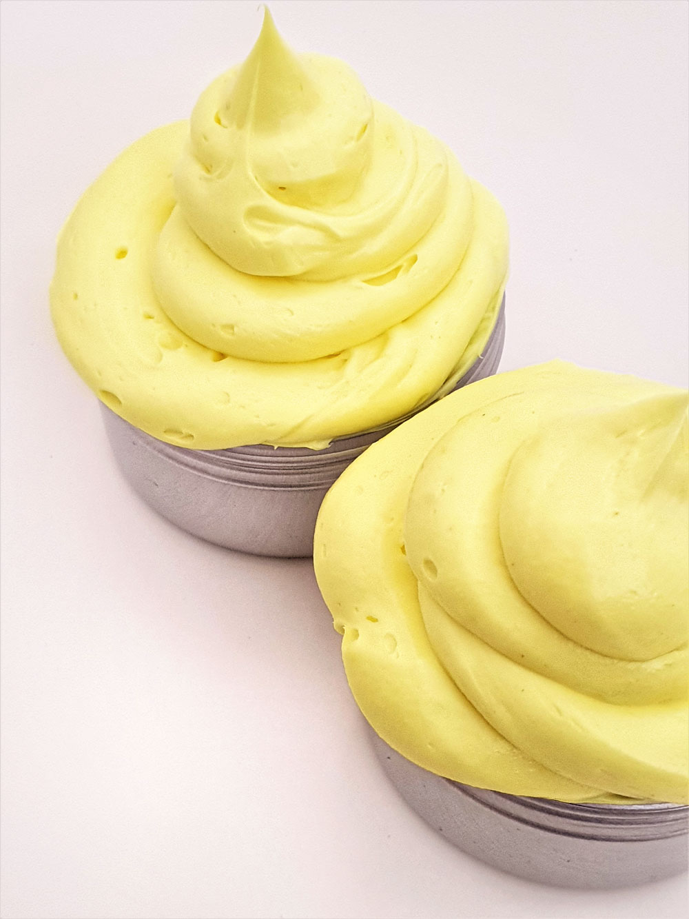 whipped turmeric body butter piped into jars with a piping bag