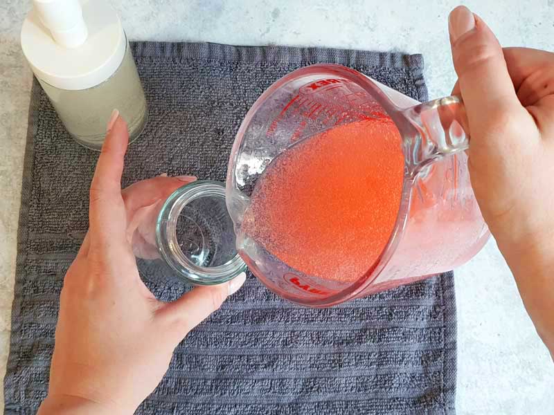pouring red soap into soap dispenser