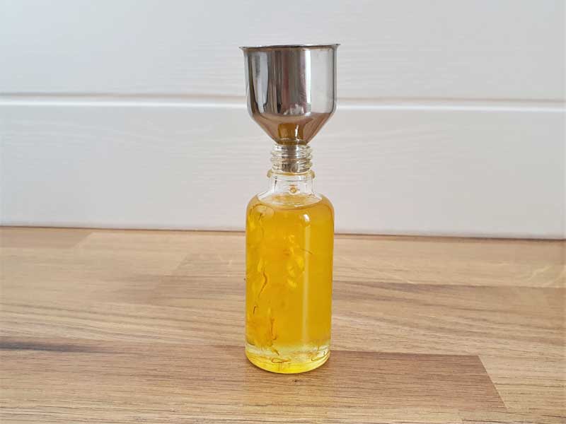 making yoni oil by filling up the bottle with oils